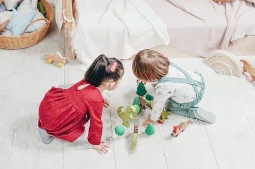 Two children, a boy and a girl, playing with toys on the floor