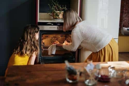 Mother and daughter using the oven in their kitchen