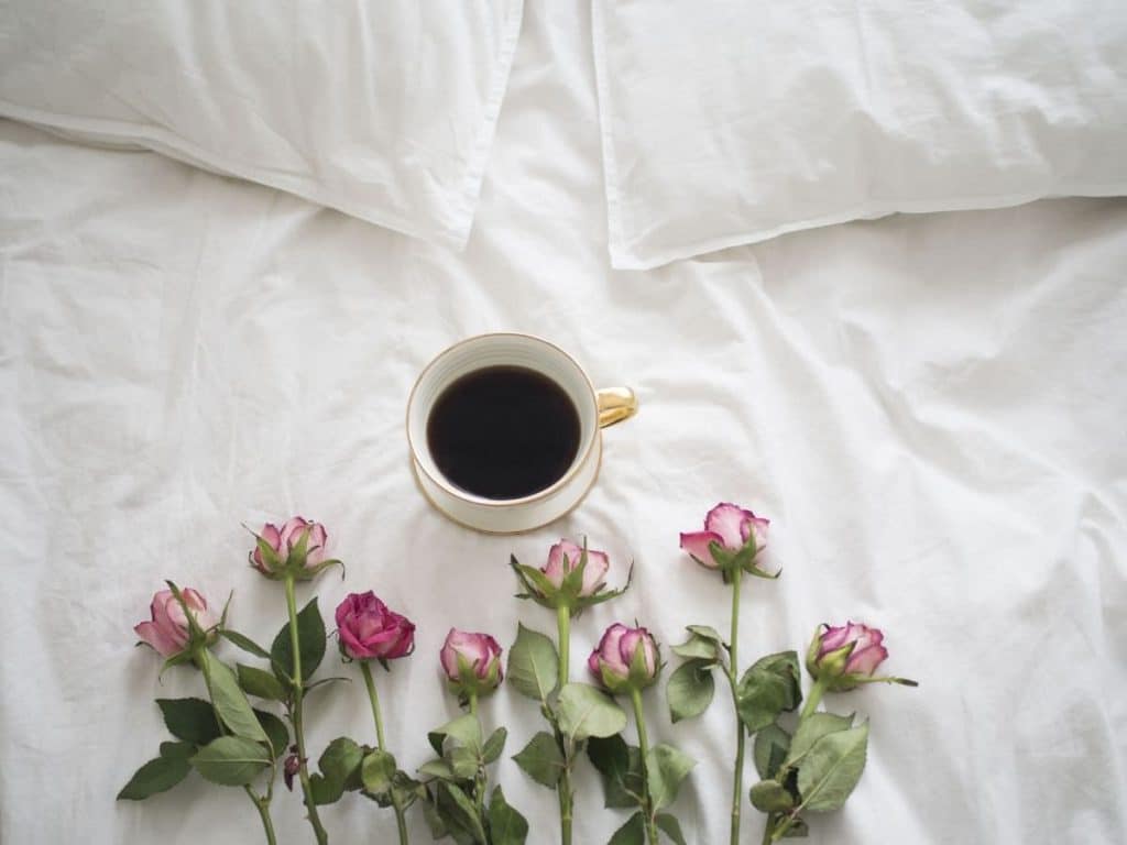 Lovely bed with cup of coffee and roses on it