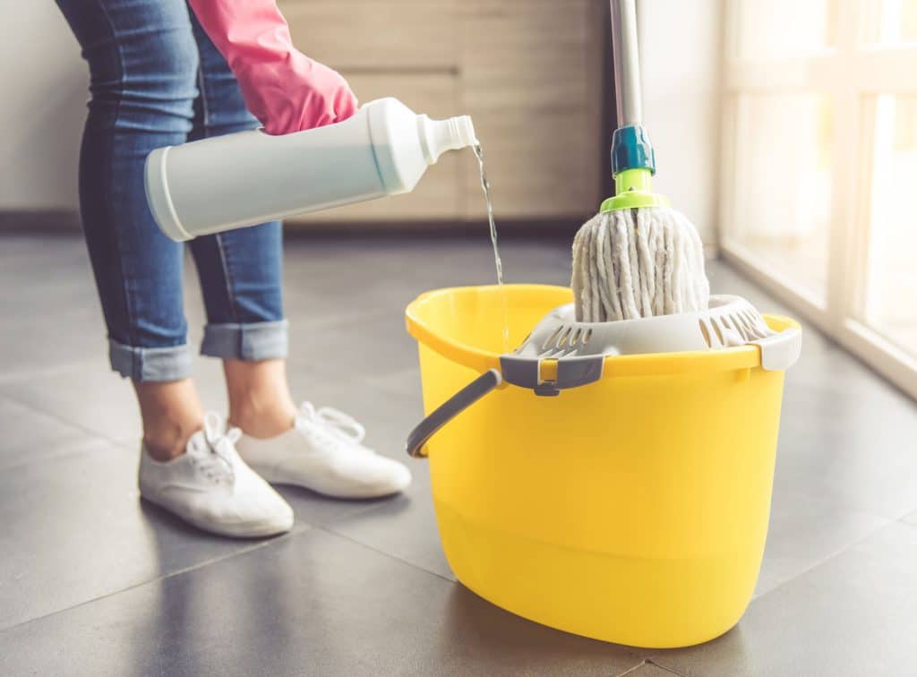 House cleaner pouring cleaning chemicals into a bucket